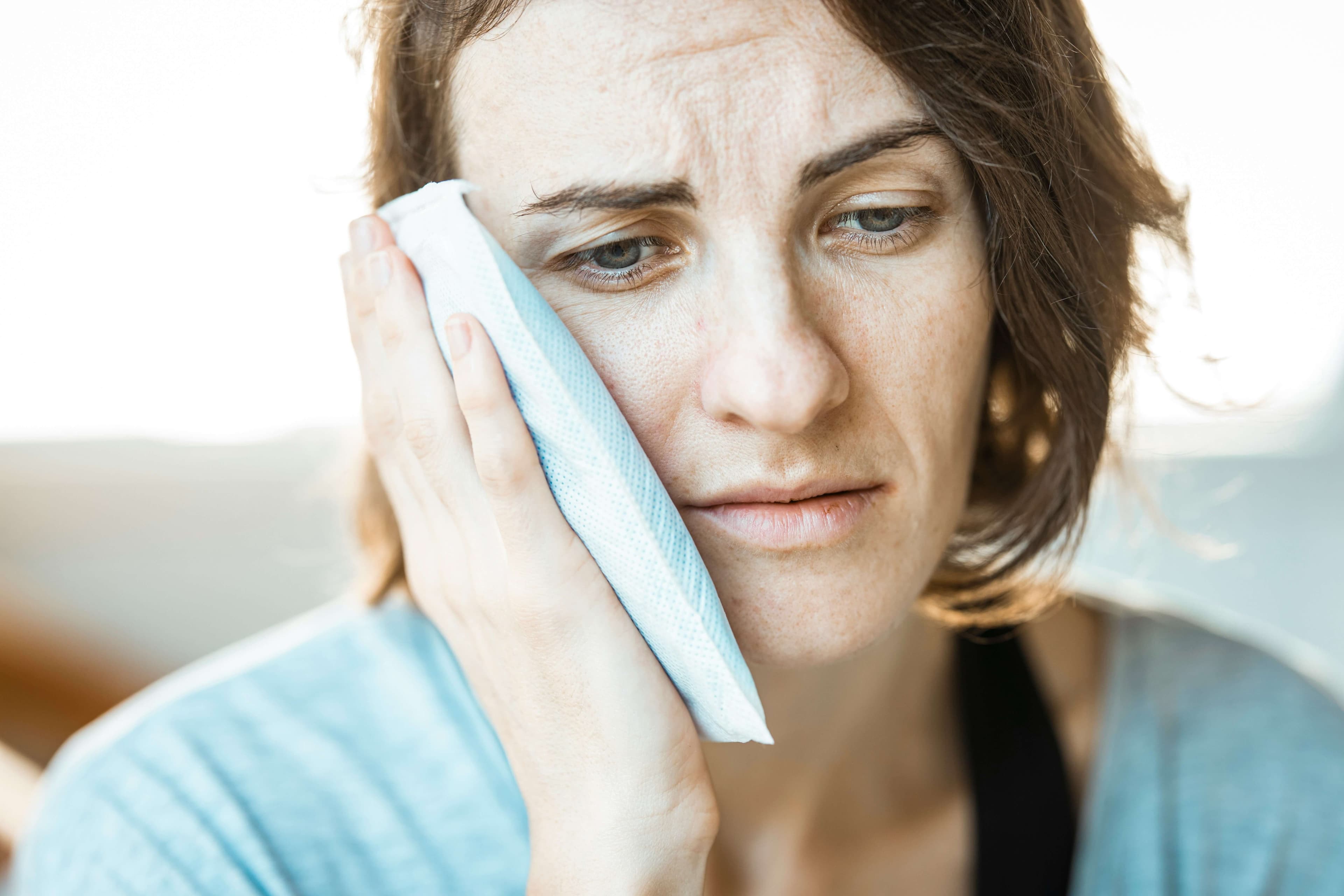 Person holding an ice pack to their face in discomfort